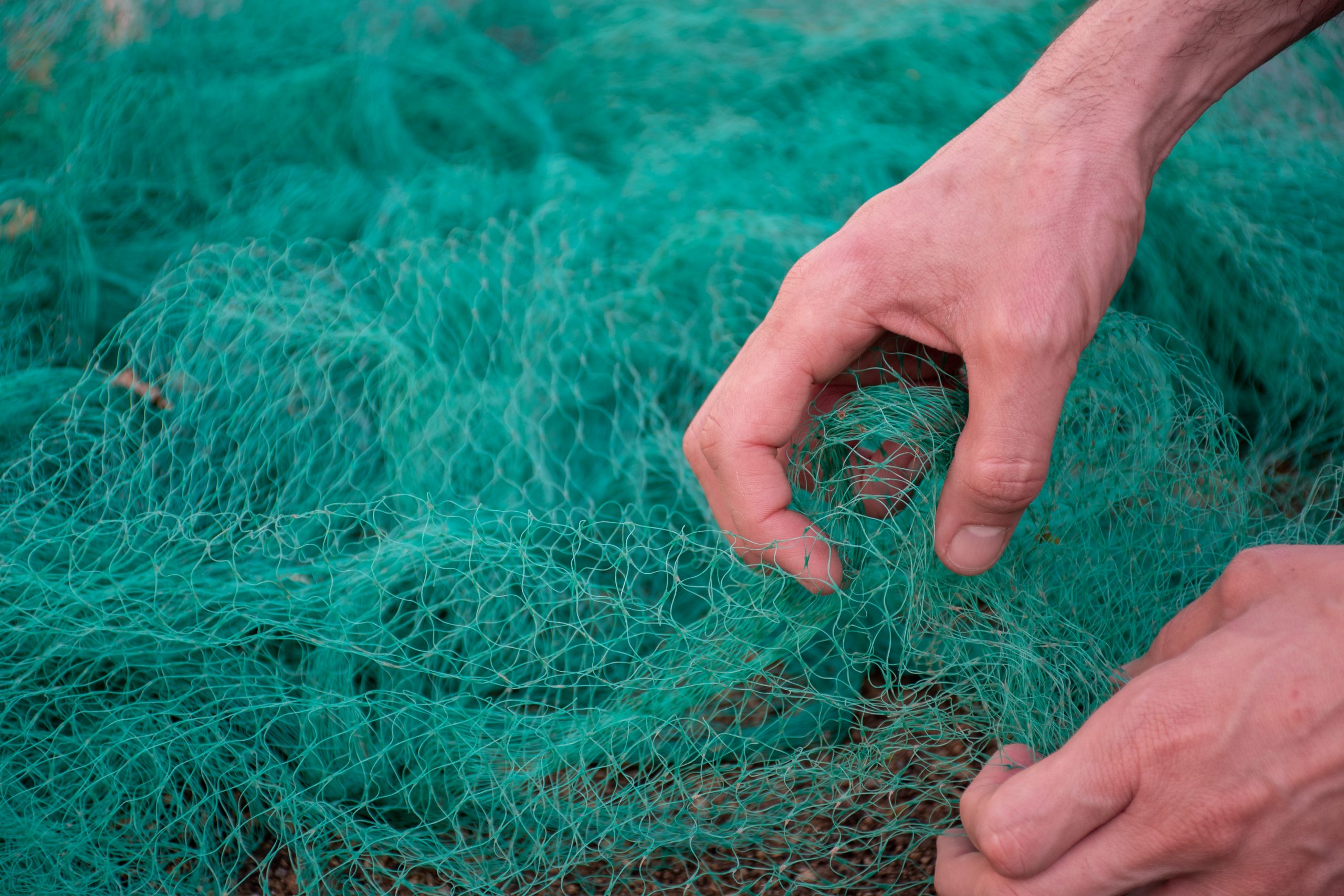 view-man-hands-picking-up-green-fishing-net-waste-nature-environmental-protection